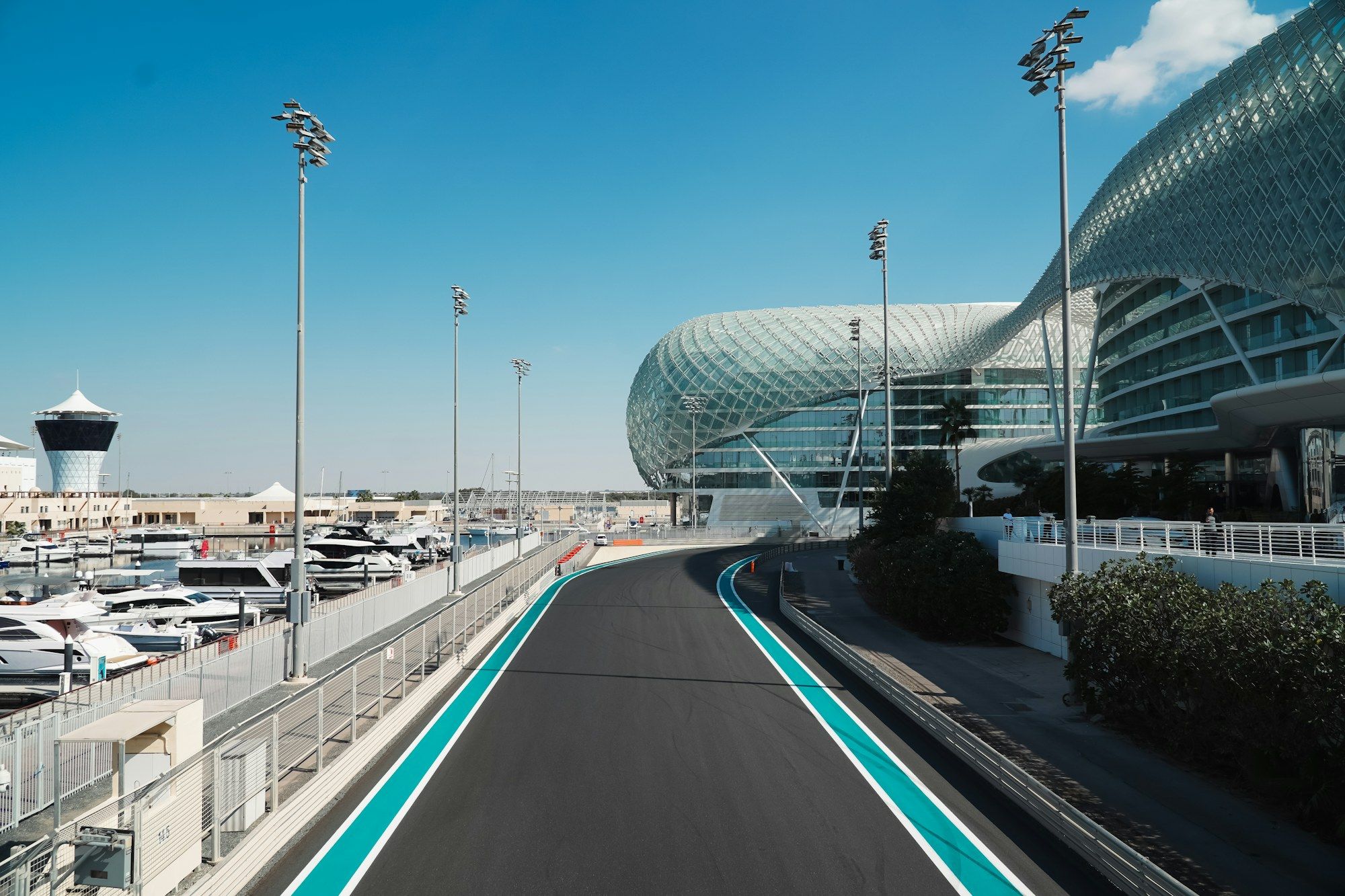 Yas Marina pistinin virajı, yanında ışıklı kabuğuyla Yas Hotel ve marinada demirli tekneler