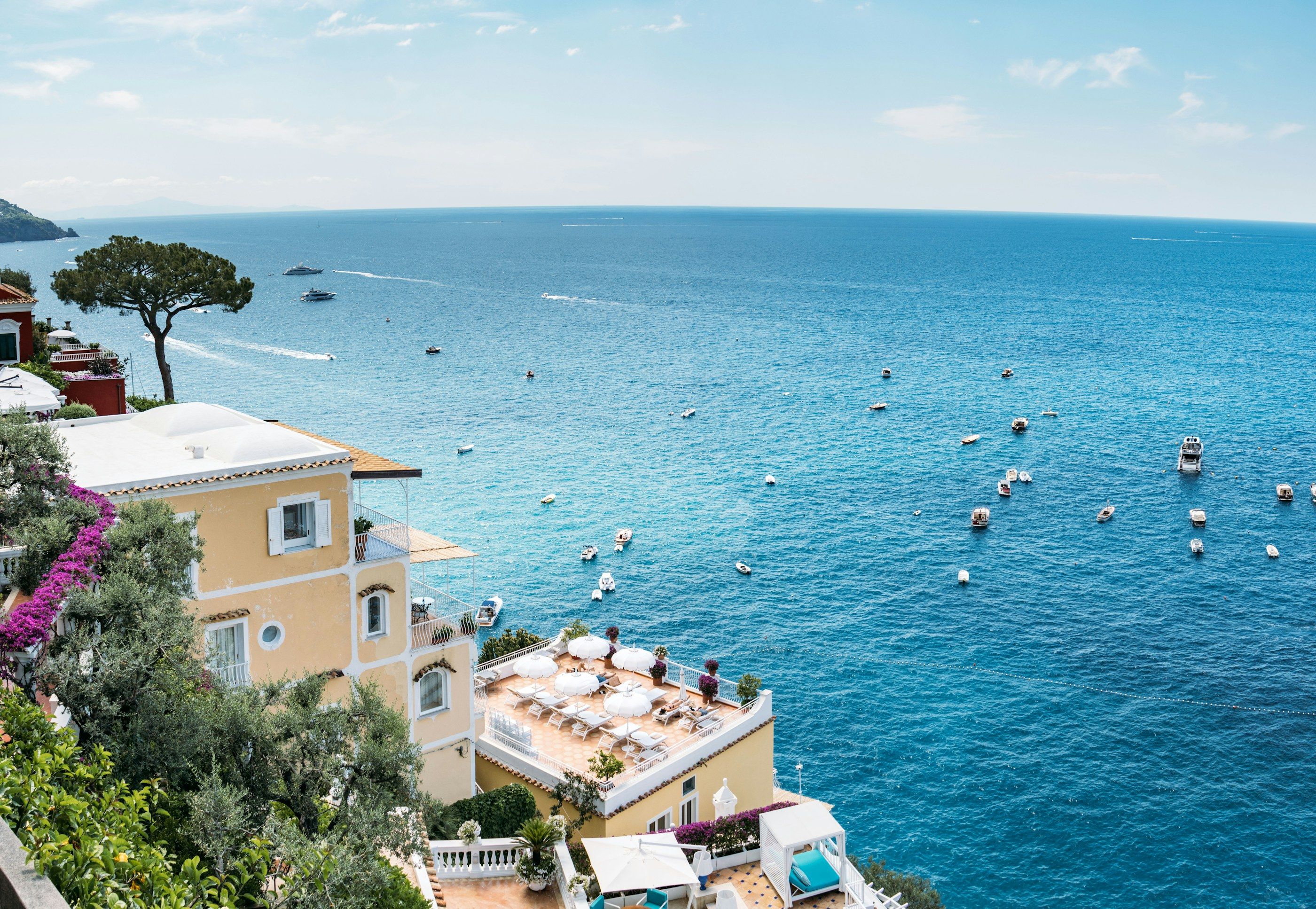 Positano’da denize bakan otel terasları, çam ağacı ve koyda demirli tekneler