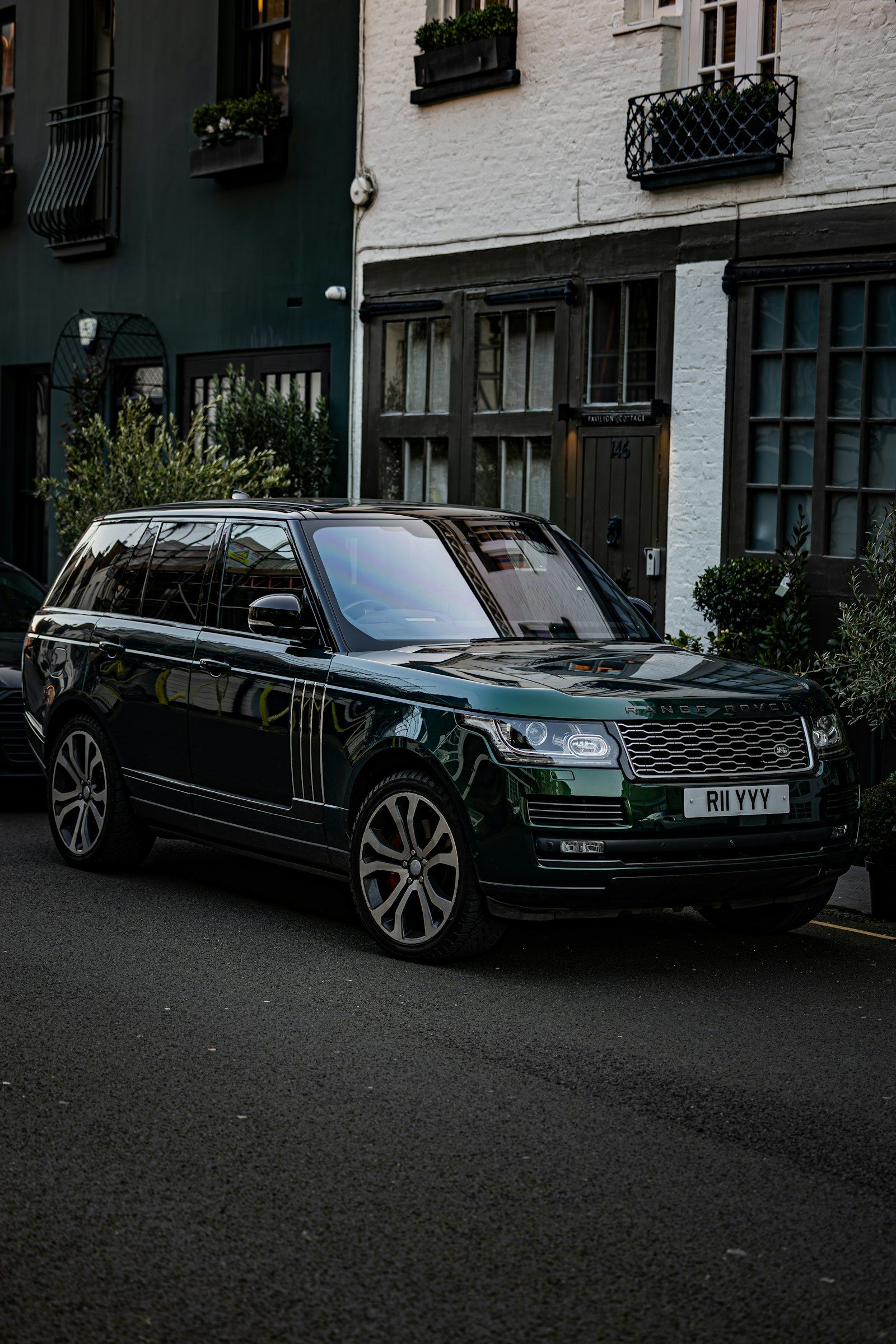 Akşam ışığında, tarihi evlerin önüne park edilmiş koyu yeşil bir Range Rover
